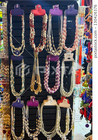 A display of shell and bead necklaces hanging on a stand. Jewelry, craftsmanship, and colorful summer fashion accessories. 130426376
