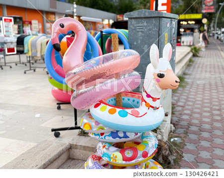Inflatable flamingo and llama floats at a street shop. Playful decoration, water fun, and summer holiday spirit. 130426421