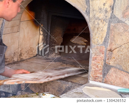 Flatbread baking inside a stone oven during traditional cooking. Culinary culture, artisan craft and gastronomy represented through baking, heat and handmade food. Flatbread baking inside a stone oven during traditional cooking. Culinary culture, artisan craft and gastronomy represented through baking, heat and handmade food. 130426552