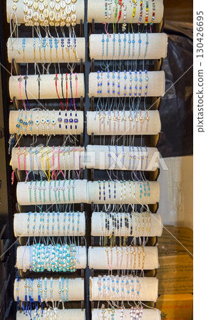 Bracelets with beads, shells and charms arranged on rolls for sale in a market. Jewelry, accessory and cultural creativity represented through consumer choice, style and artisan design. Bracelets with beads, shells and charms arranged on rolls for sale in a market. Jewelry, accessory and cultural creativity represented through consumer choice, style and artisan design. 130426695