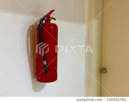 Red fire extinguisher mounted on a wall indoors. Safety, protection and emergency preparedness in a public or private space. Red fire extinguisher mounted on a wall indoors. Safety, protection and emergency preparedness in a public or private space. 130426742