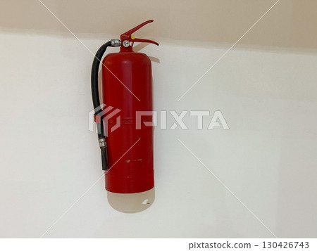 Red fire extinguisher mounted on a wall indoors. Safety, protection and emergency preparedness in a public or private space. 130426743
