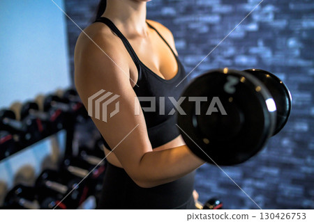Woman lifting dumbbell with one hand. Cool woman exercising at the gym. Upper body. Muscle training girl. Faceless part cutout. 130426753