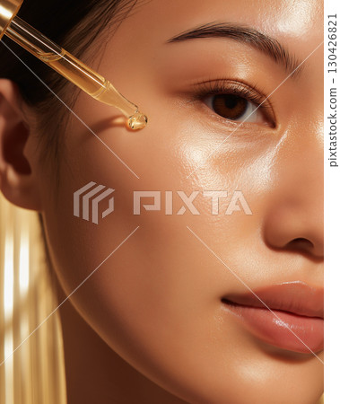 Glowing skin with drop of serum from golden dropper in close-up view representing healthy skincare and moisture 130426821