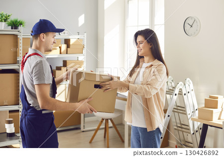 Man from delivery service working in warehouse with female small business owner in logistics center 130426892