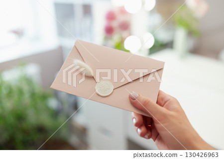 Close up on present envelope in hand of a cosmetologist beautician. Getting and receiving discounts or present certificates for cosmetological procedures 130426963