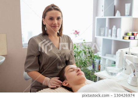 Portrait of a doctor beautician with female client in her cabinet. Cosmetologist ready to do her job, perform some rejuvenation, skincare procedures to the girl client 130426974