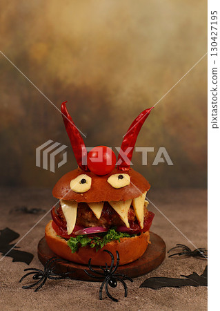 Halloween food concept. Scary hamburgers with fresh lettuce, tomatoes, cream cheese, lettuce, onions, cutlets and peppers in the form of horns on an old concrete background, cafe advertising 130427195