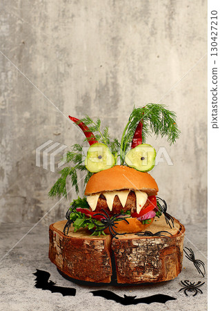 Halloween food concept. Scary hamburgers with fresh lettuce, tomatoes, cream cheese, lettuce, onions, cutlets and peppers in the form of horns on an old concrete background, cafe advertising, menu Halloween food concept. Scary hamburgers with fresh lettuce, tomatoes, cream cheese, lettuce, onions, cutlets and peppers in the form of horns on an old concrete background, cafe advertising, menu 130427210