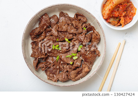 Bulgogi, grilled marinated beef Korean dish with kimchi and sesame seeds top view on white background Bulgogi, grilled marinated beef Korean dish with kimchi and sesame seeds top view on white background 130427424