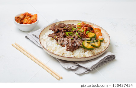 Korean beef bulgogi bowl dish with rice, roasted meat, kimchi and marinated cucumber on white background with chopsticks Korean beef bulgogi bowl dish with rice, roasted meat, kimchi and marinated cucumber on white background with chopsticks 130427434