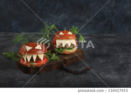 Halloween food concept. Scary hamburgers with fresh parsley leaves, tomatoes, cream cheese, lettuce, onion and cutlet on an old concrete background, food delivery, cafe advertising, 130427453