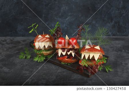 Halloween food concept. Scary burgers with fresh parsley leaves, tomatoes, cream cheese, onion and cutlet on old concrete background, low key, food delivery, cafe advertisement, Halloween food concept. Scary burgers with fresh parsley leaves, tomatoes, cream cheese, onion and cutlet on old concrete background, low key, food delivery, cafe advertisement, 130427458