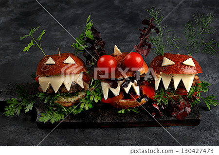 Halloween food concept. Scary hamburgers with fresh parsley leaves, tomatoes, cream cheese, lettuce, onion and cutlet on an old concrete background, food delivery, cafe advertising, 130427473