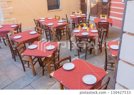 Traditional Italian cafe with tables prepared for dinner, rustic chairs and colorful decor. Perfect scene for gastronomy, travel and hospitality concepts in Mediterranean lifestyle. 130427533