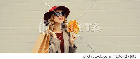 Autumn portrait of beautiful happy woman with shopping bag, stylish girl holding yellow leaves Autumn portrait of beautiful happy woman with shopping bag, stylish girl holding yellow leaves 130427692