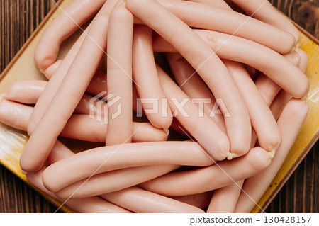 Raw sausages stacked on a ceramic plate, ready for cooking, rustic wooden background Raw sausages stacked on a ceramic plate, ready for cooking, rustic wooden background 130428157