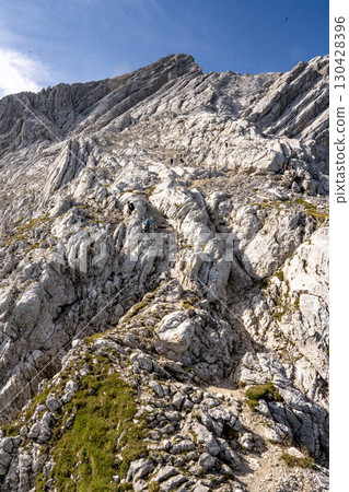 Rocky Section Of The Via Ferrata Alpspitze In The Bavarian Alps: Dramatic Cliffs And Mountain Peaks Under Scenic Blue Sky 130428396