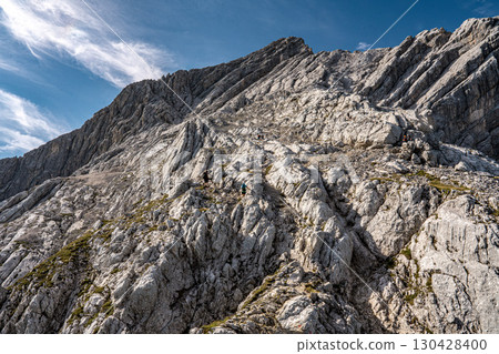 Rocky Section Of The Via Ferrata Alpspitze In The Bavarian Alps: Dramatic Cliffs And Mountain Peaks Under Scenic Blue Sky Rocky Section Of The Via Ferrata Alpspitze In The Bavarian Alps: Dramatic Cliffs And Mountain Peaks Under Scenic Blue Sky 130428400
