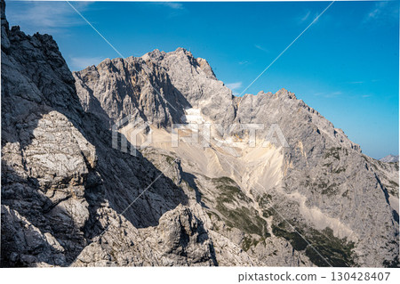 Scenic View Of Zugspitze And Jubilee Ridge From Via Ferrata Alpspitze: Rugged Rocky Peaks Of The Bavarian Alps Under Clear Blue Sky Scenic View Of Zugspitze And Jubilee Ridge From Via Ferrata Alpspitze: Rugged Rocky Peaks Of The Bavarian Alps Under Clear Blue Sky 130428407