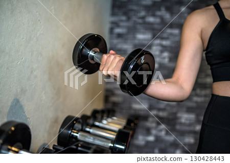 Woman choosing dumbbell weight, picking up, cool woman exercising at the gym, muscle training girl, part cut, no face Woman choosing dumbbell weight, picking up, cool woman exercising at the gym, muscle training girl, part cut, no face 130428443