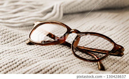 Stylish eyeglasses placed on a cozy knit fabric to beautifully enhance your look and comfort Stylish eyeglasses placed on a cozy knit fabric to beautifully enhance your look and comfort 130428637