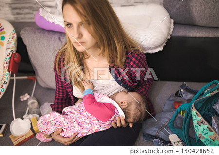 Mother breastfeeding her baby at home in a cozy living room 130428652