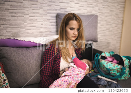 Tired Mom breastfeeds her baby daughter at home Tired Mom breastfeeds her baby daughter at home 130428653