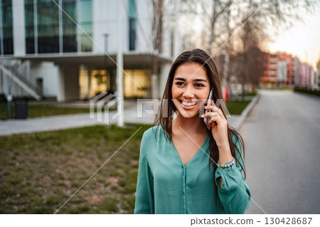 Young woman smiling while talking on phone in the city 130428687