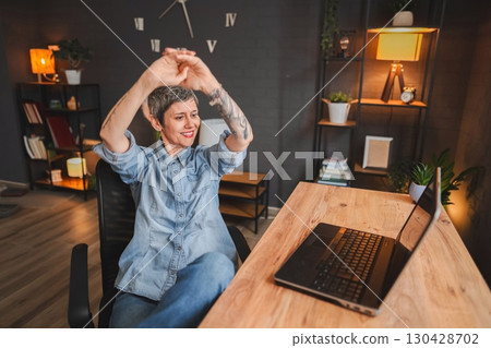 Freelancer woman stretching arms while working from home office 130428702