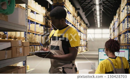 Woman employee placing adhesive shipping labels on boxes in depot, labeling packages with awb tracking numbers to ensure seamless express delivery and order processing. Camera A. 130428703
