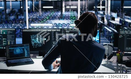 Data center computer scientist using PC to monitor neural network using AI LLM. IT expert at work using artificial intelligence to oversee servers powering machine learning, camera A 130428725