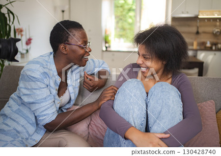 Two women talking and laughing during a therapy session on a sofa 130428740