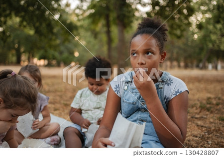 Children eating snacks and watching a movie in the park Children eating snacks and watching a movie in the park 130428807