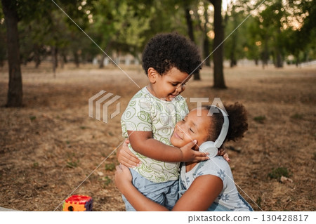 Older Sister Hugging Younger Brother at the Park 130428817