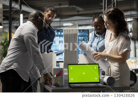 Real estate experts analyzing blueprints and models next to green screen, working on new urban development project through planning phases and infrastructure design. Urban growth. 130428826