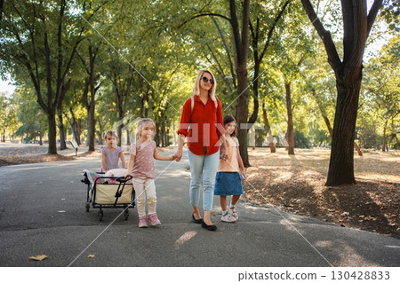 Mother and daughters walking in the park, pulling a wagon Mother and daughters walking in the park, pulling a wagon 130428833