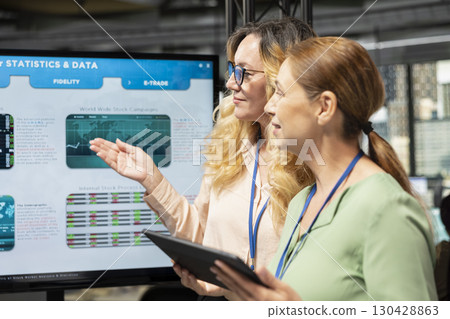 Empowered business associates planning a project with development goals, meeting in a boardroom to review data insights and performance indicators for multinational company growth. 130428863