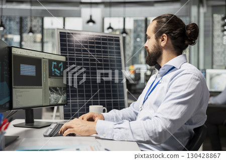 Engineer working for green tech company uses CAD program to optimize sustainable solar panel fabrication with advanced assembly lines. Clean energy professional innovates solar manufacturing processes 130428867