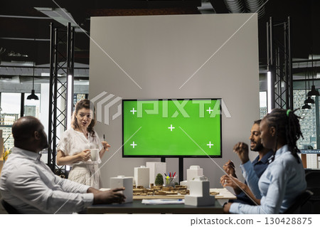 Real estate developers use green screen and architectural blueprints to collaborate in a smart city innovation hub, planning a modern residential project with infrastructure and investment goals. 130428875