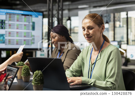 Ambitious focused businesswoman at desk reviewing business strategy after collecting reports data and performance indicators, aligning development goals driven by success. Report writing. 130428876