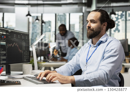 Portfolio manager uses trading platform on PC to review assets performance and adjusts holdings. Prop firm worker oversees diversified investment portfolios on computer to maximize returns for clients 130428877