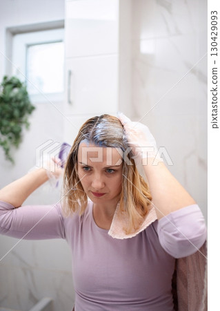Woman dyeing her hair at home in the bathroom 130429093