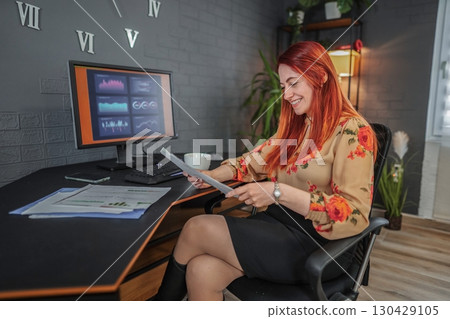 Businesswoman analyzing financial reports and working on computer in office 130429105