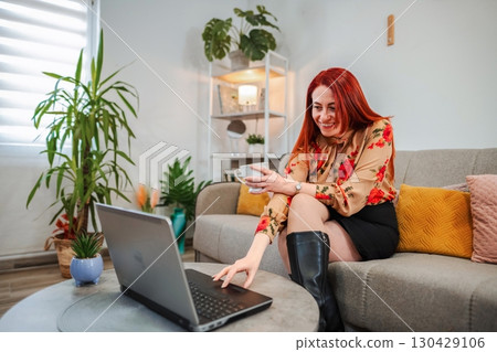 Happy businesswoman working from home, drinking coffee and using laptop Happy businesswoman working from home, drinking coffee and using laptop 130429106