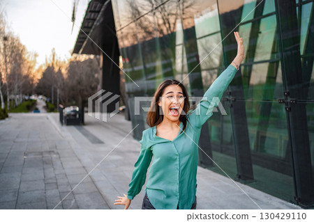 Excited businesswoman celebrating success in front of modern office building Excited businesswoman celebrating success in front of modern office building 130429110