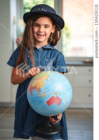 Smiling schoolgirl learning geography with a globe at home Smiling schoolgirl learning geography with a globe at home 130429118