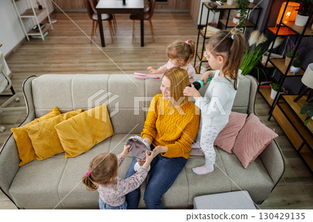 Three little girls are doing their mom's hair 130429135