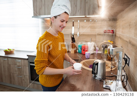Woman makes herself a coffee in the kitchen Woman makes herself a coffee in the kitchen 130429138