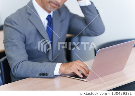 Senior businessman thinking while looking at a computer 130429381